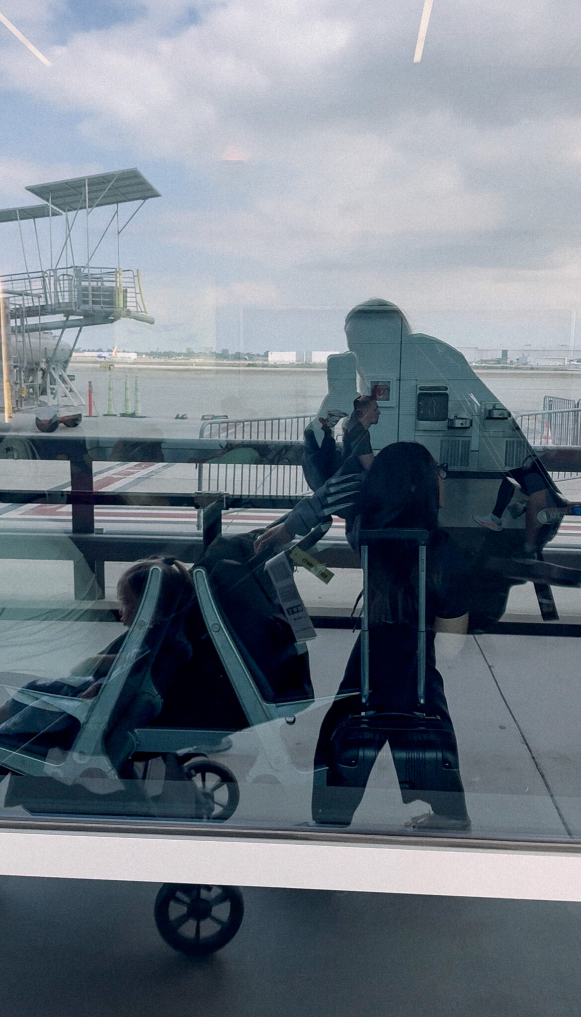 mom walking onto a plane with a travel stroller and travel carseat