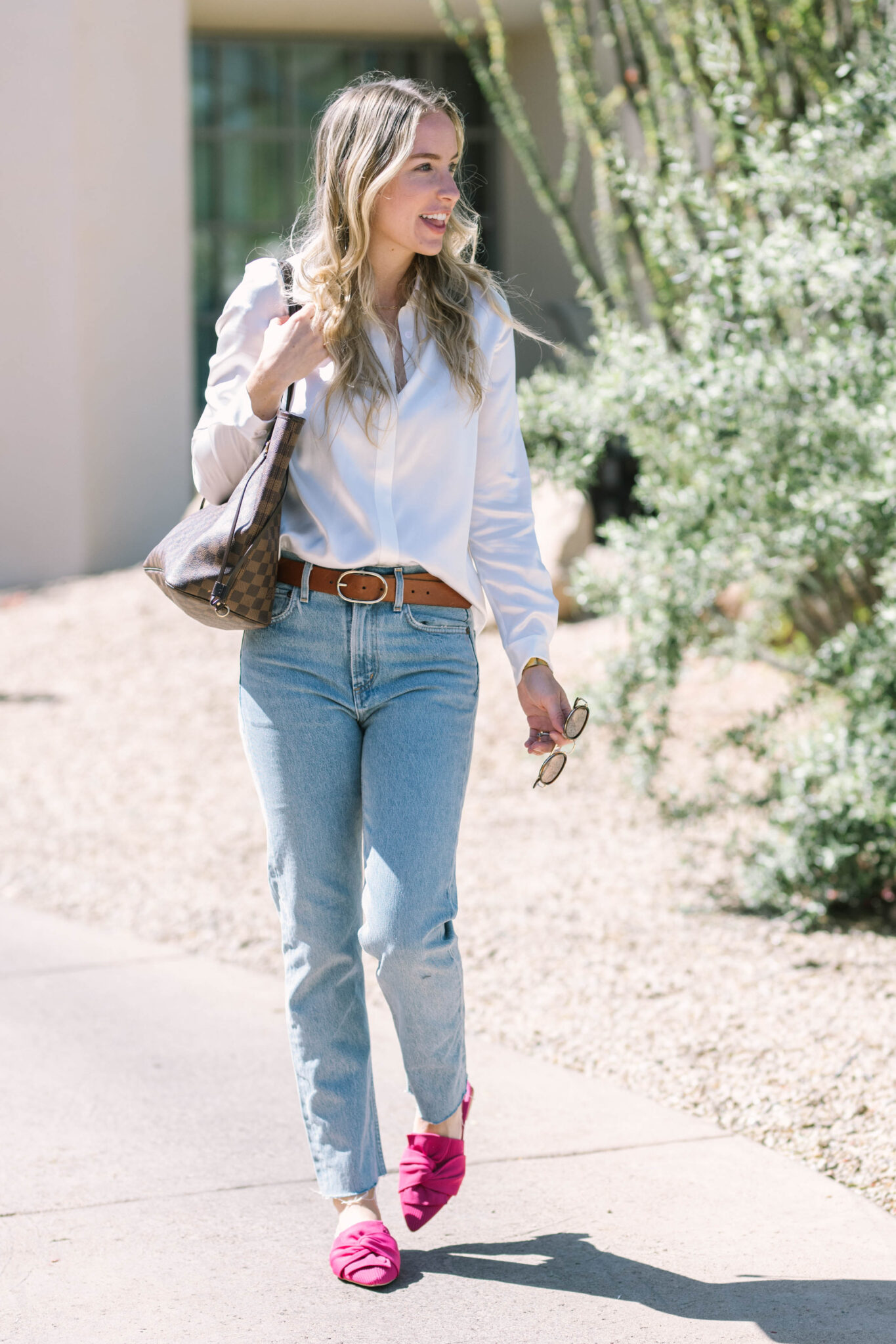 woman wearing her louis vuitton neverfull with denim and a white buttondown.