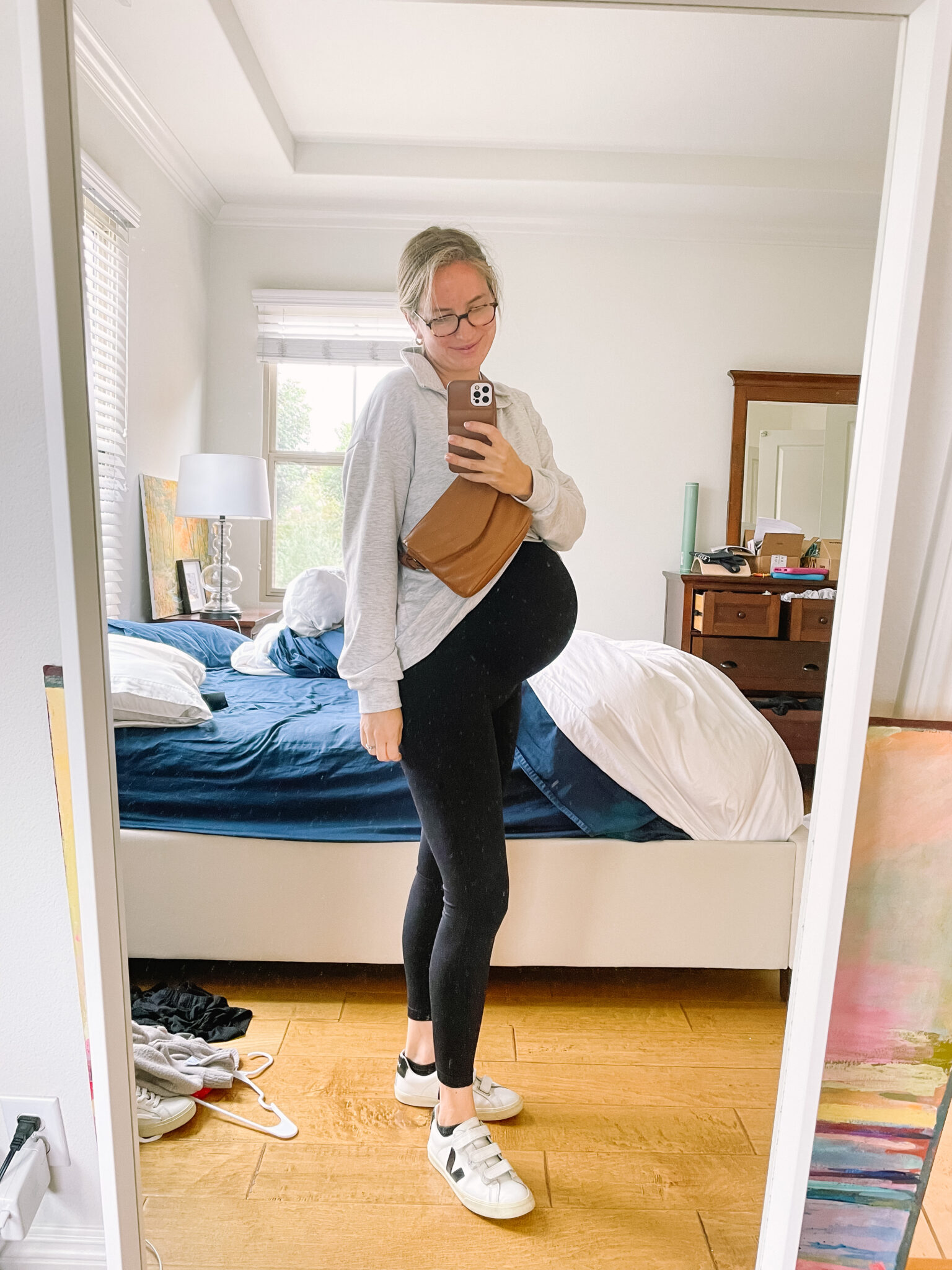 Pregnant mom in black maternity leggings, a gray cardigan and white sneakers, best maternity leggings from a mom of 4