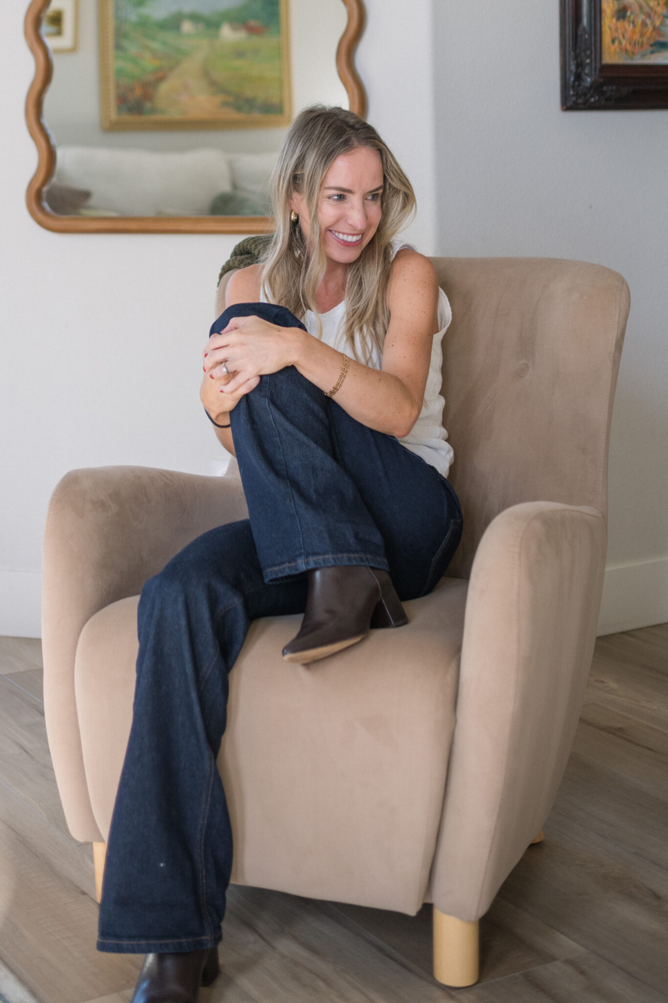 Elisabeth seated in Mott & Bow Gilmore wide leg jeans in dark blue with brown heeled boots